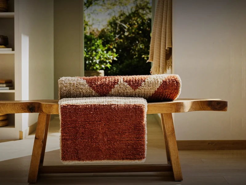 Fladvævet kilim i terracotta og creme over en træbænk i entréen
